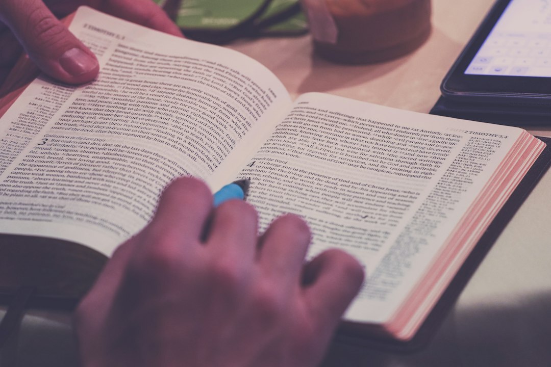 Close-up of hands writing notes beside an open book